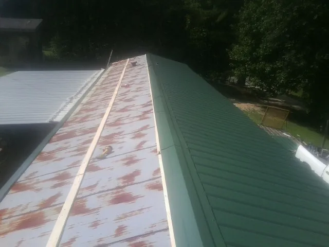 Old rusted panels beside newly installed green metal roofing — Wind Damage Roof Repair by Roofing Brothers in Browntown