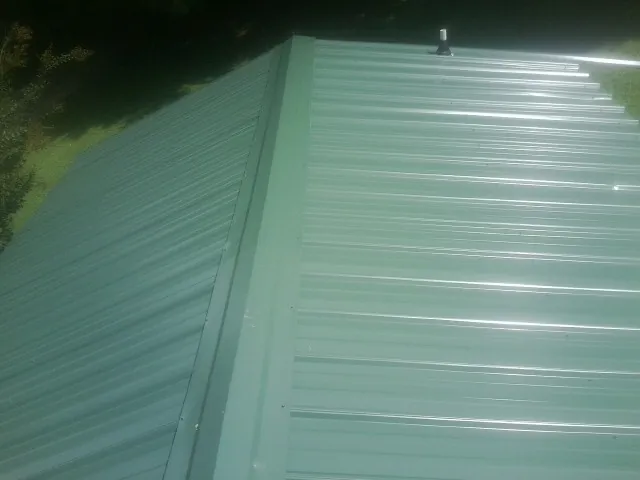 New green metal panels meeting at the ridge of a roof — Flat Roof Repair work by our crew in Browntown