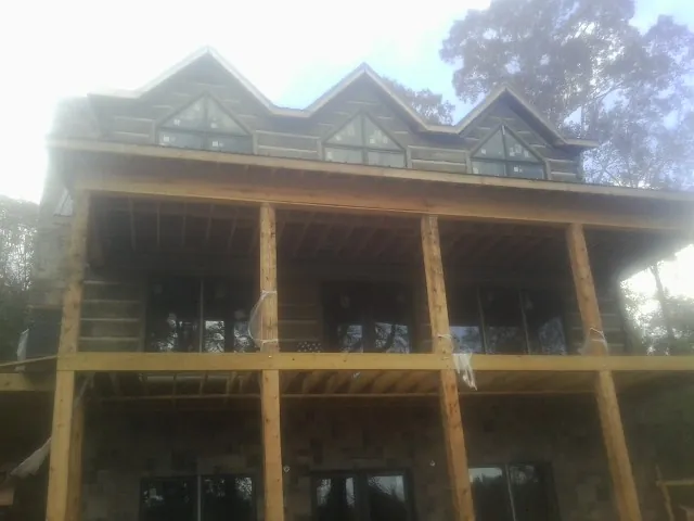 Dormers and porch framing on a large log home under construction — Roof Coating work by our crew in Browntown