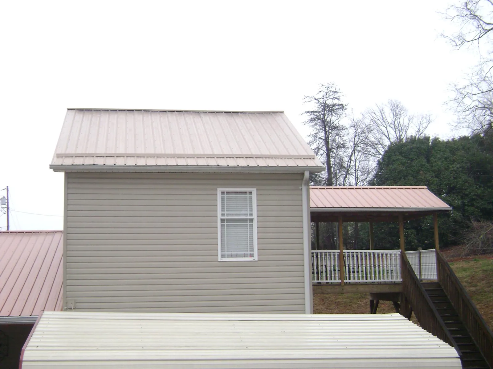 Tan metal roofs on a two story addition and attached porch, from a Roof Replacement job in Browntown