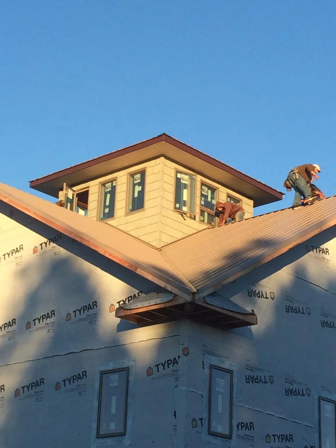 Roofers working around a rooftop cupola on a new metal roof at sunset — Roof Waterproofing in Browntown by Roofing Brothers
